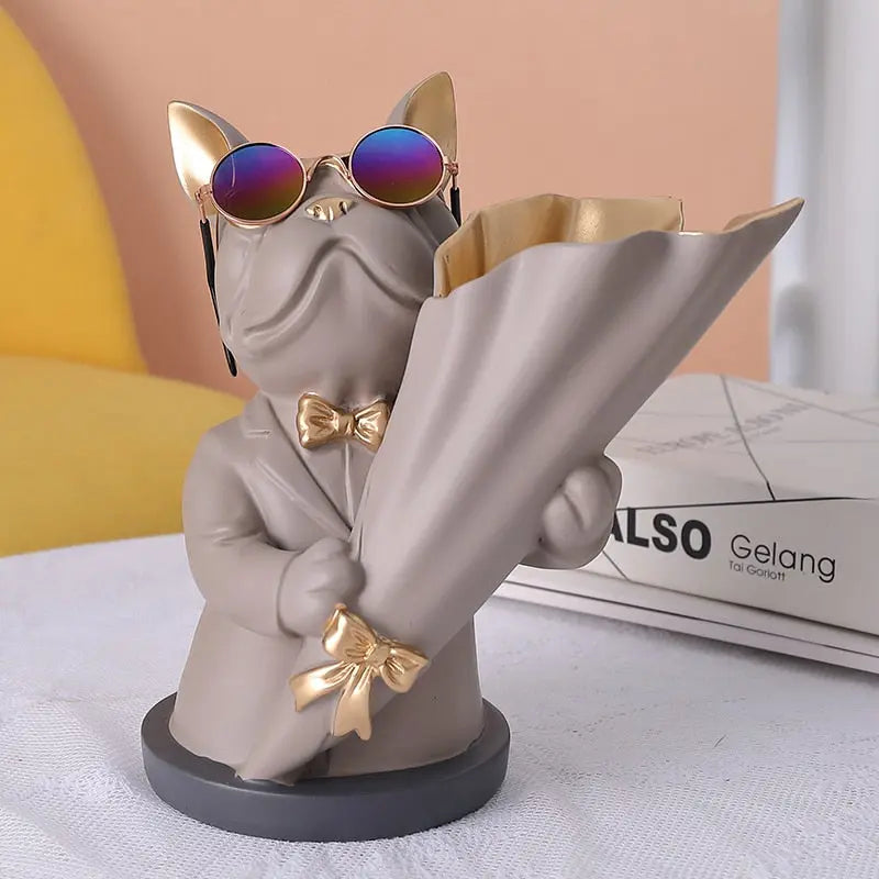 Cat-shaped vase with sunglasses and a bow tie holding an umbrella on a light surface.