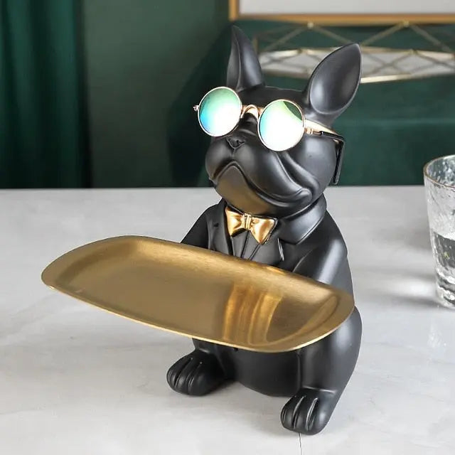 Black dog figurine with sunglasses and a gold tray on a white surface