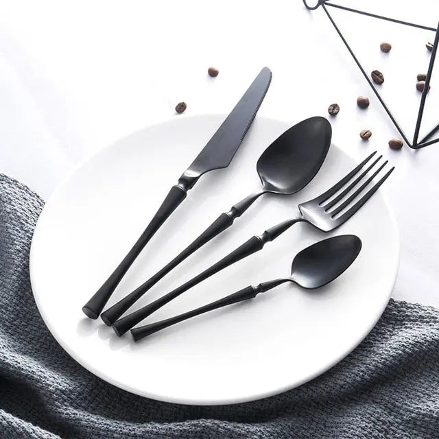 Black cutlery set on a white plate with a geometric black design in the background.