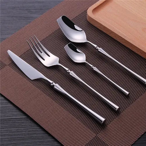 Set of silver cutlery including knife, fork, and spoons on a brown placemat.