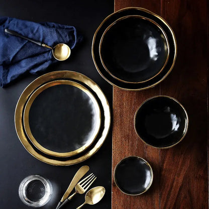 Black and gold ceramic plates on a dark surface with silverware.