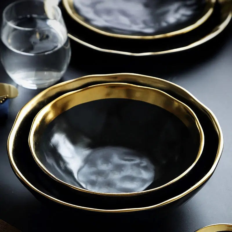 Set of black plates with gold rims on a dark surface
