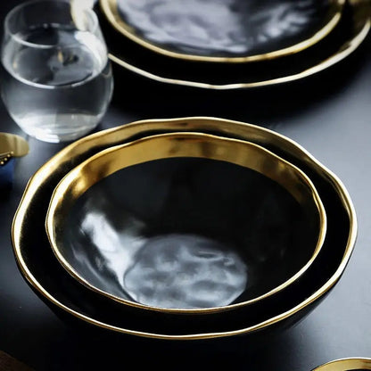Set of black plates with gold rims on a dark surface