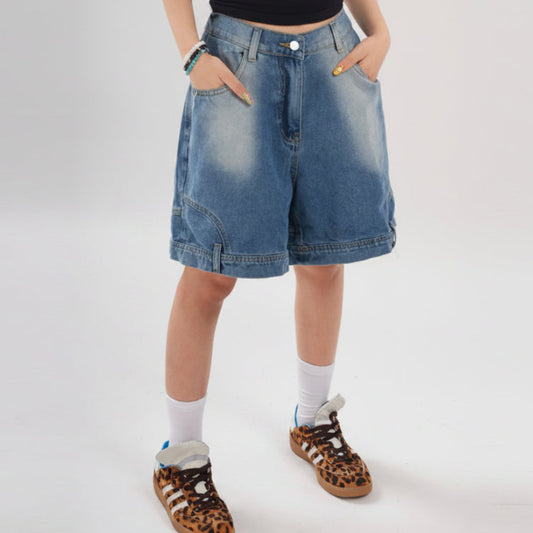 Person wearing blue denim shorts on a white background