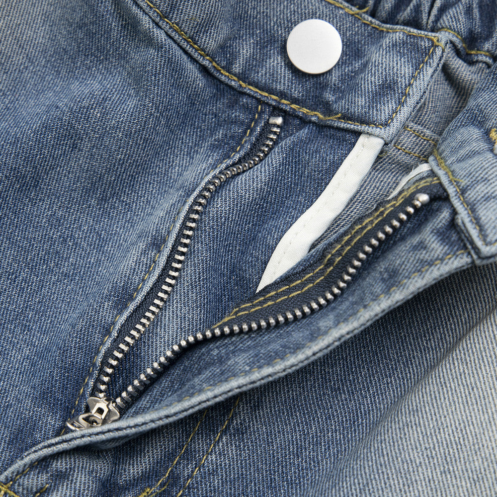 Close-up of a blue denim jacket with a zipper and button detail.