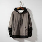 Gray hoodie on a wooden hanger against a textured gray wall