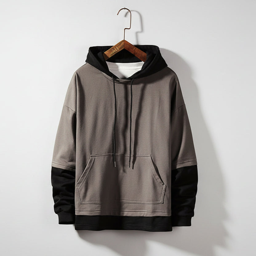 Gray hoodie on a wooden hanger against a textured gray wall
