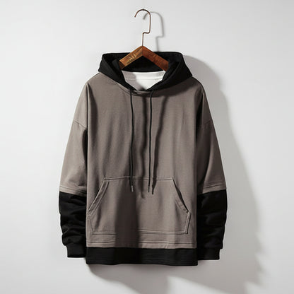 Gray hoodie on a wooden hanger against a textured gray wall