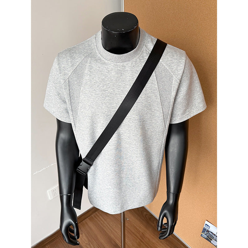 Gray t-shirt on a black mannequin with a black strap against a neutral background