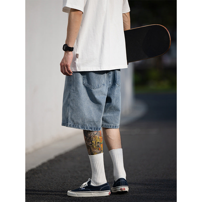 Person wearing a white t-shirt, blue denim shorts, and white socks, holding a skateboard.