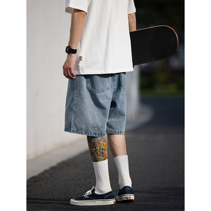 Person wearing a white t-shirt, blue denim shorts, and white socks, holding a skateboard.