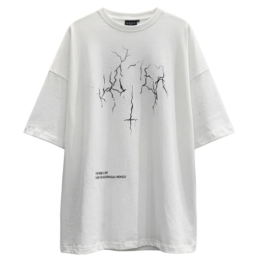 Person wearing a white oversized t-shirt with black graphics against a plain wall.