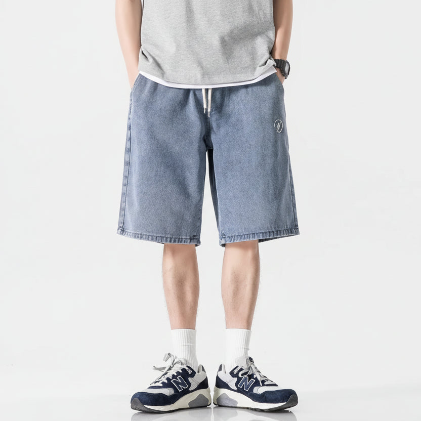 Person wearing blue denim shorts with additional shorts displayed below on a white background