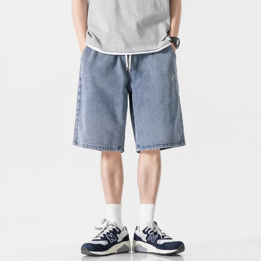 Person wearing blue denim shorts with additional shorts displayed below on a white background