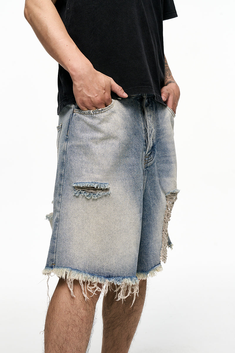 Person wearing a black shirt and distressed denim shorts on a white background