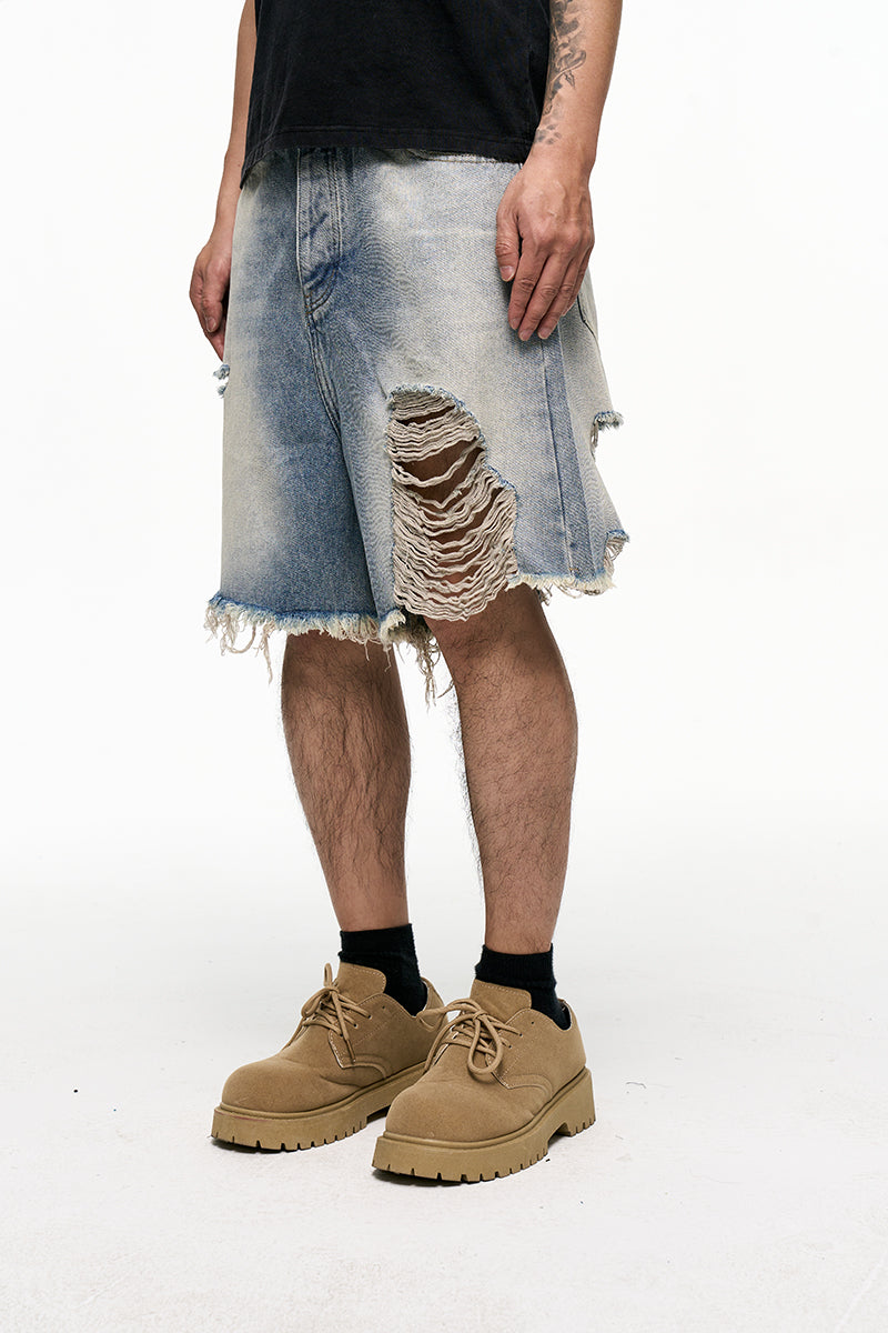 Person wearing distressed denim shorts and tan boots on a white background