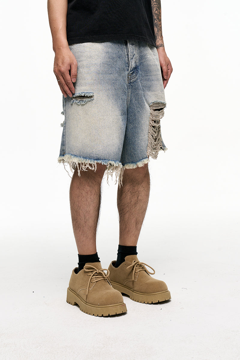 Person wearing distressed denim shorts and tan boots on a white background