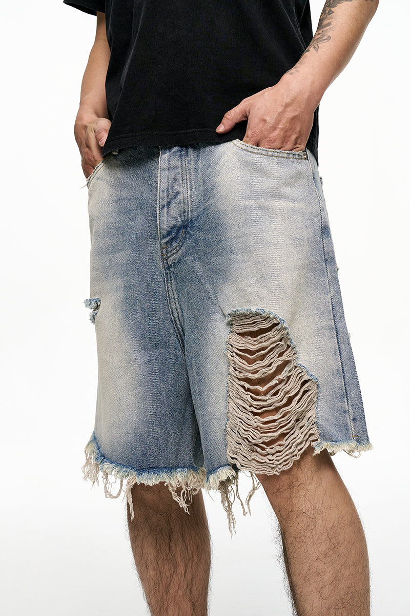 Ripped denim shorts worn by a person on a white background