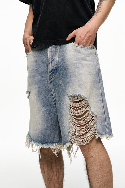 Ripped denim shorts worn by a person on a white background