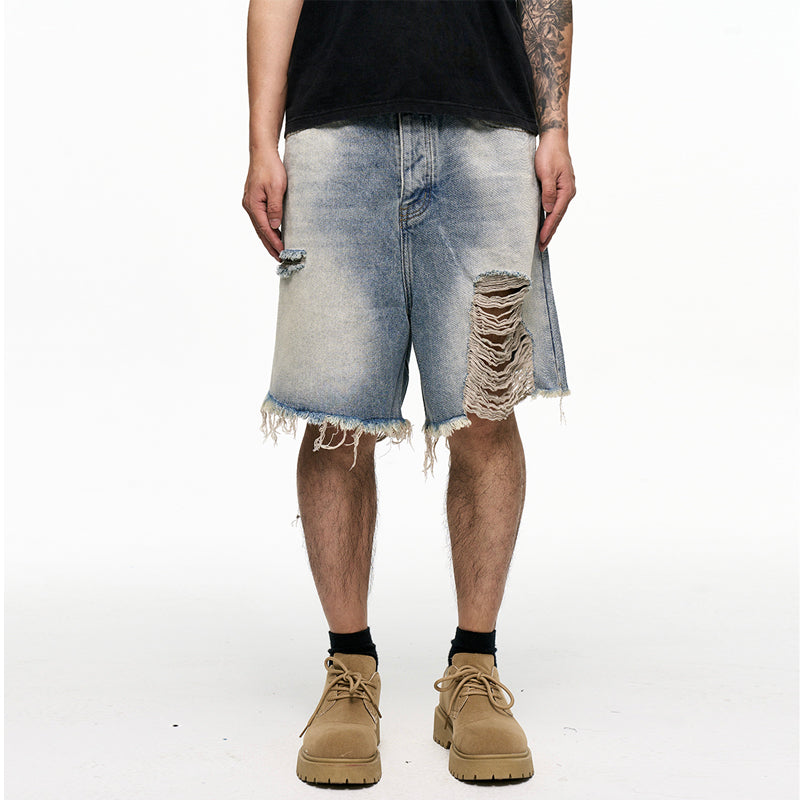 Person wearing distressed denim shorts on a white background