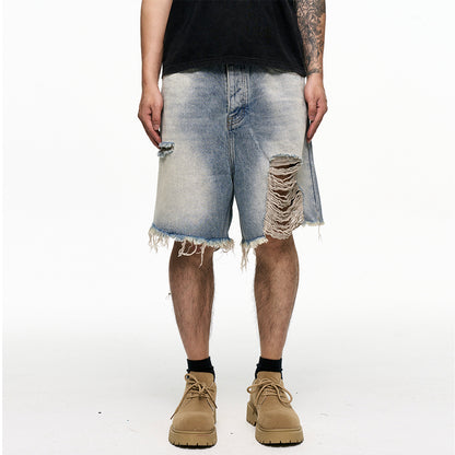 Person wearing distressed denim shorts on a white background