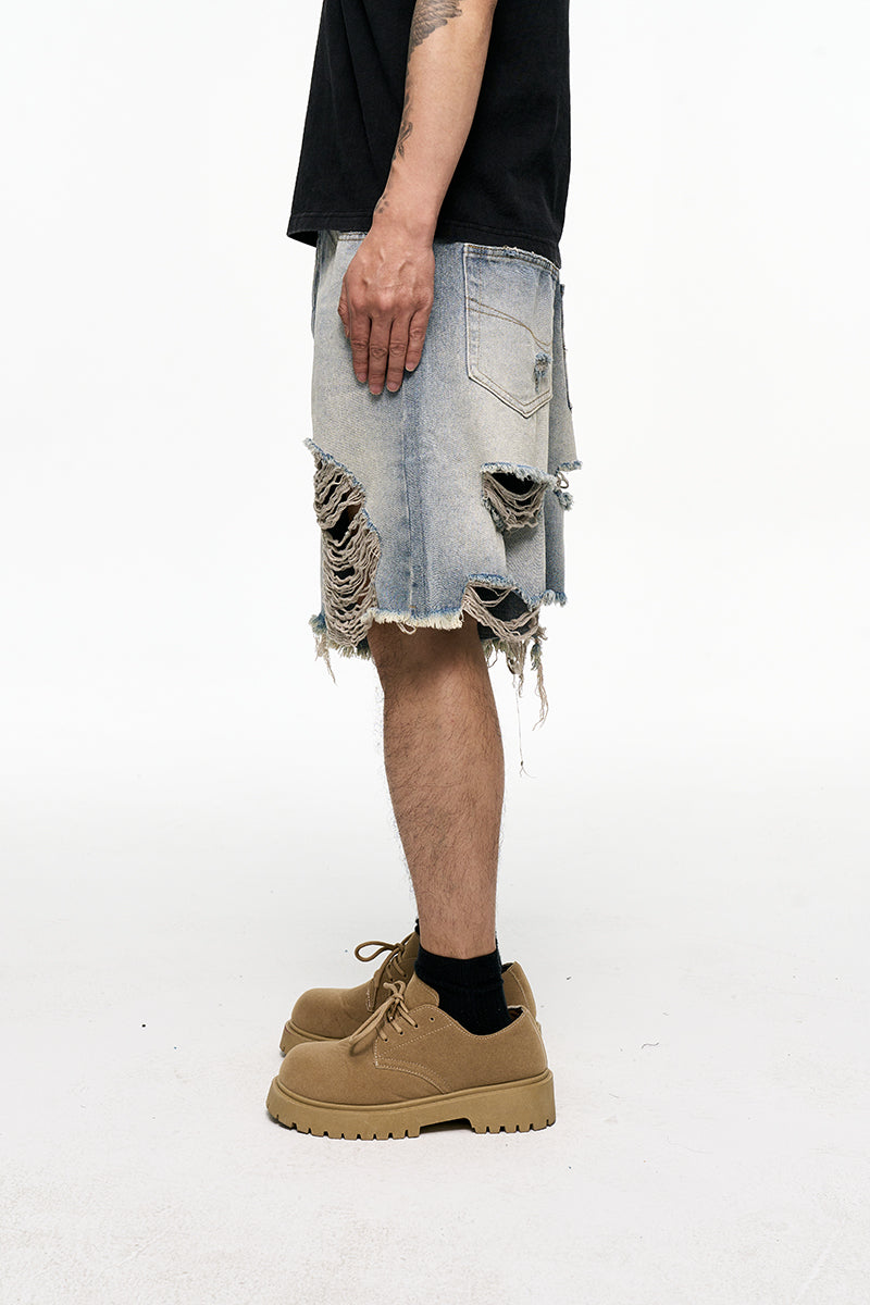Person wearing a black t-shirt, ripped denim shorts, and tan boots on a white background