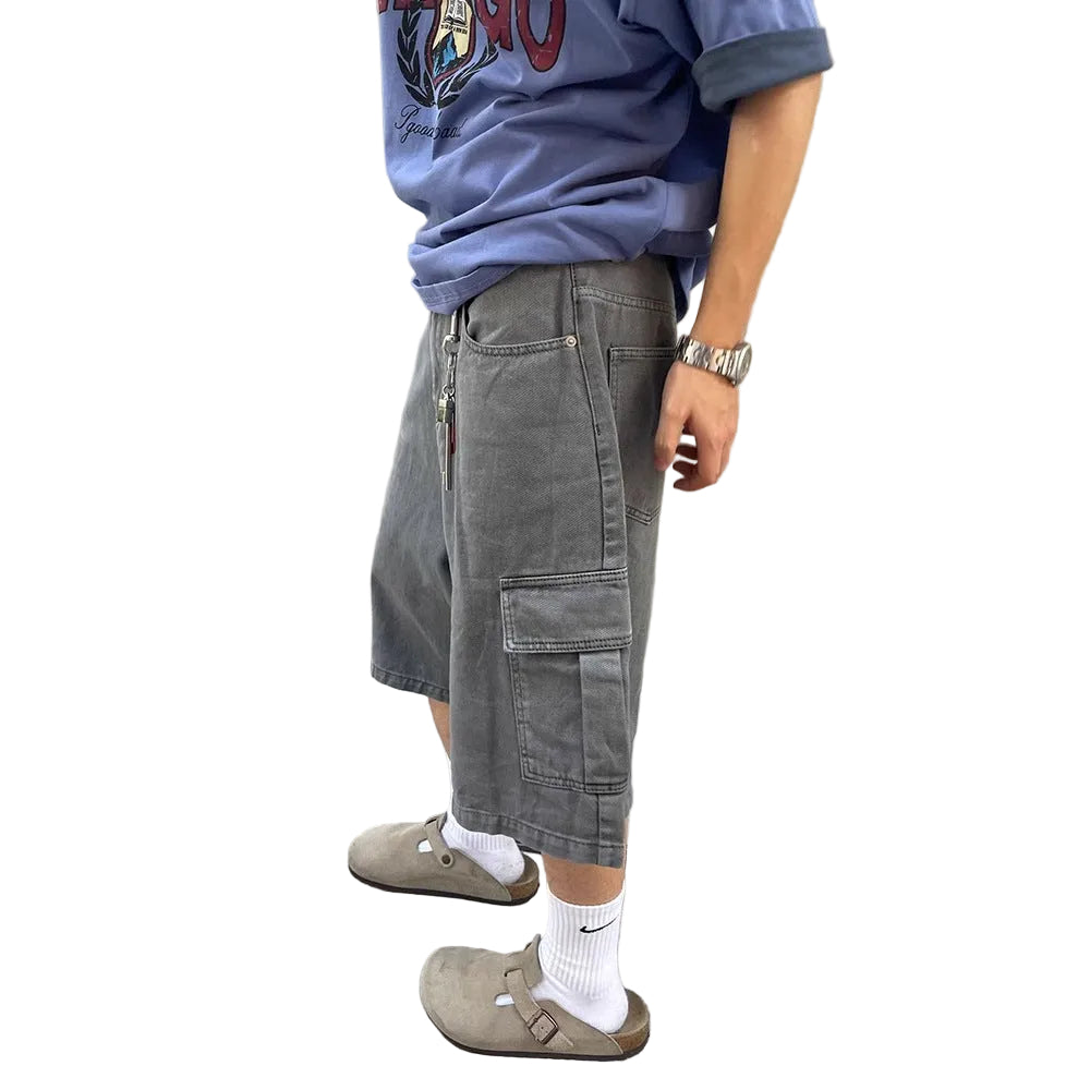 Person wearing gray cargo shorts and a blue shirt against a concrete wall.