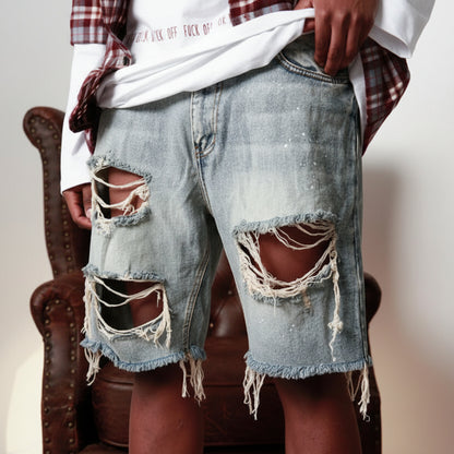 Person wearing ripped denim shorts sitting on a chair with a neutral background