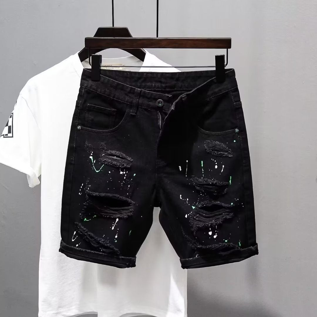 Black distressed denim shorts on a hanger with a white t-shirt in the background.