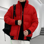 Person wearing a red puffer jacket with a black backpack indoors.